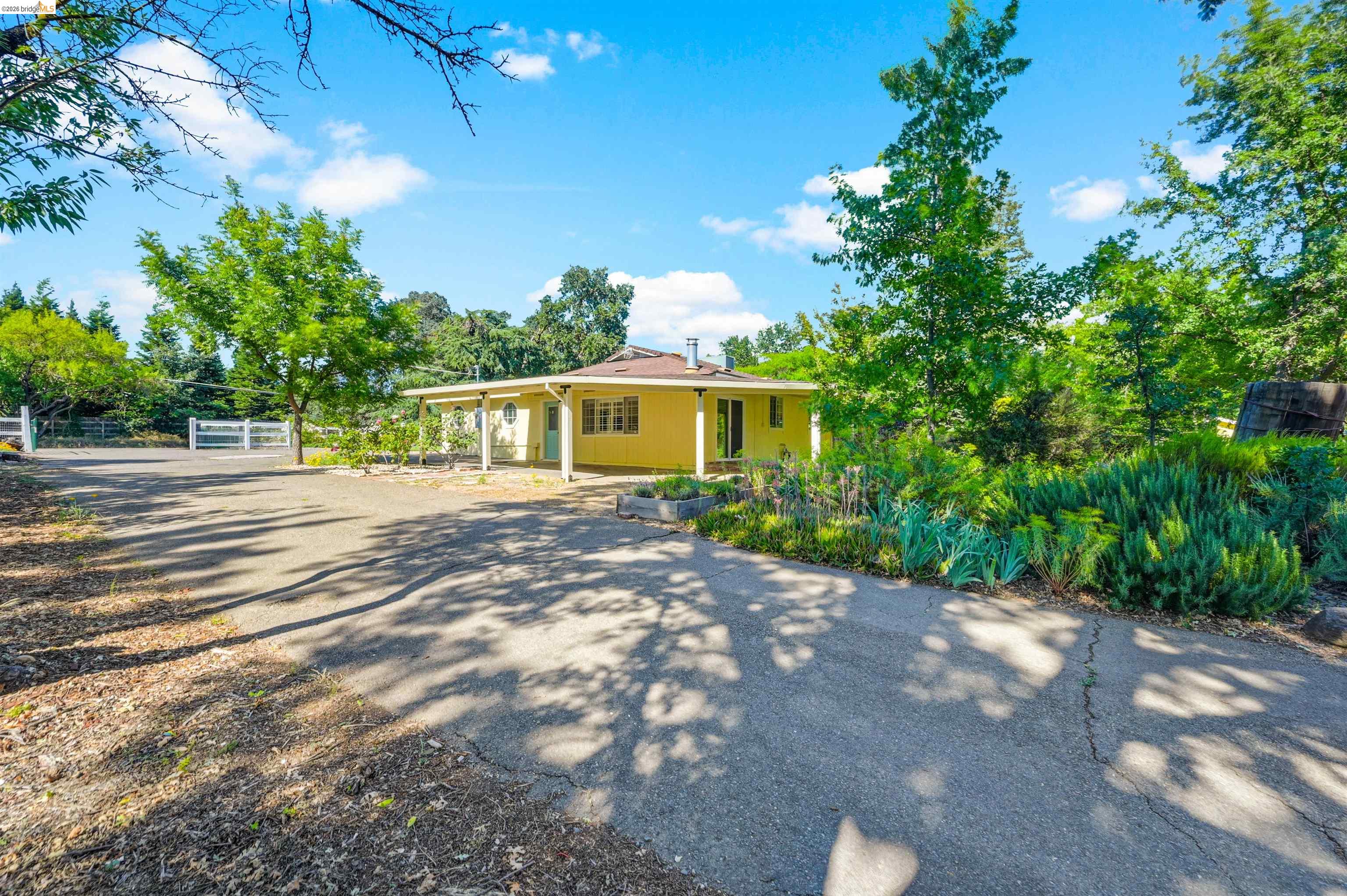 10474 Sheldon Road Elk Grove, CA 95624 - Photo 7 of 83 Yellow-sided residence featuring a covered front porch with white columns, a dark roof, and a turquoise front door