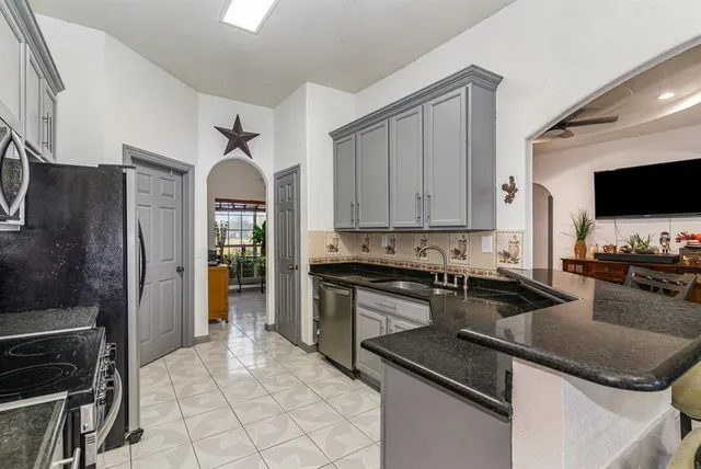 a kitchen with granite countertop a stove sink and refrigerator