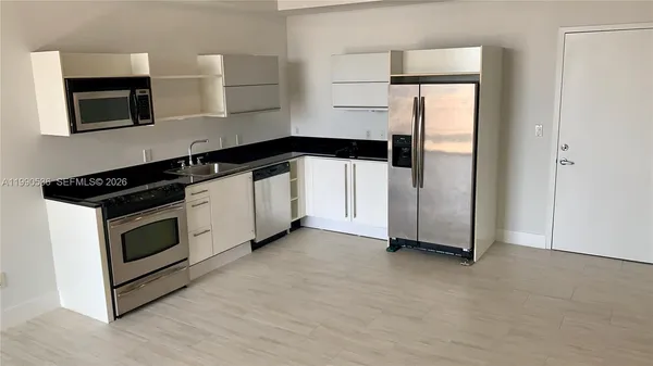 a kitchen with granite countertop white cabinets and refrigerator