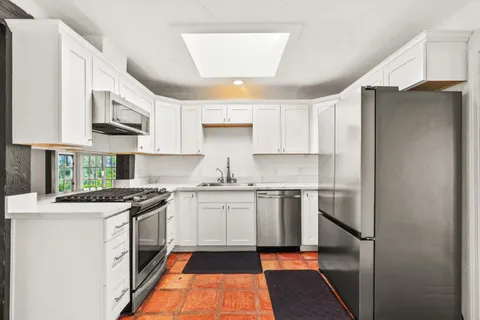 a kitchen with stainless steel appliances granite countertop a stove a sink and a microwave