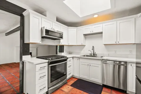 a large white kitchen with stainless steel appliances granite countertop a refrigerator and cabinets