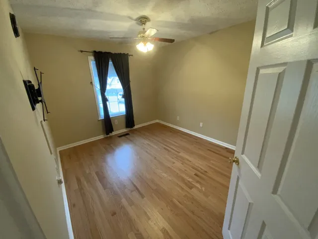 an empty room with wooden floor and windows