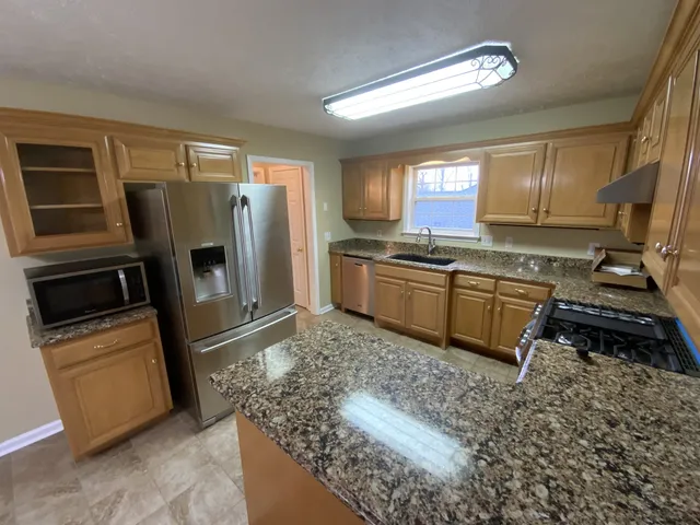 a kitchen with stainless steel appliances granite countertop a refrigerator sink and stove