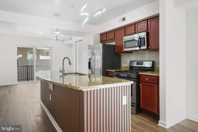 a kitchen with stainless steel appliances granite countertop a sink and dishwasher a stove top oven with wooden floor