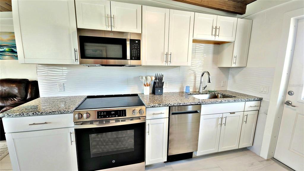 Undisclosed Address Englewood, FL 34223 - Photo 9 of 24 a kitchen with granite countertop a stove top oven microwave and cabinets