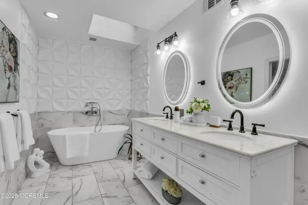 a spacious bathroom with a double vanity sink mirror and bathtub