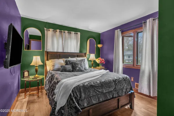 a bedroom with a bed a mirror on dresser and a window