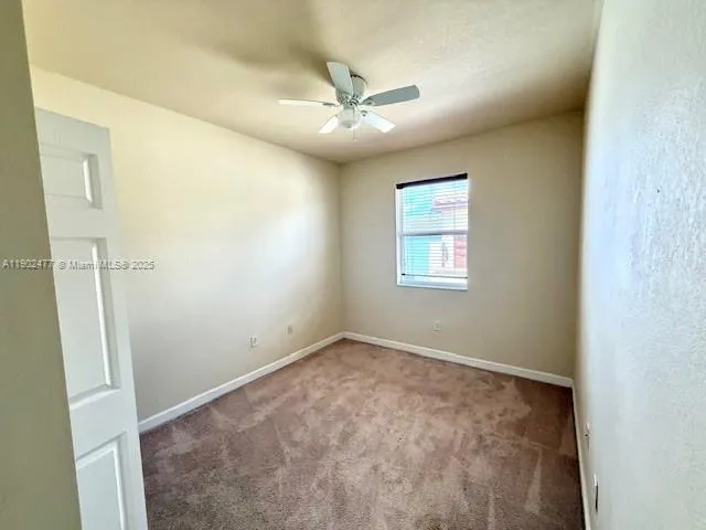 an empty room with a window and a fan