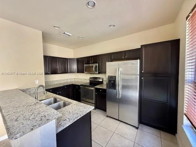 a kitchen with stainless steel appliances granite countertop a refrigerator a stove and a sink