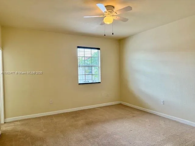 an empty room with a window and a ceiling fan