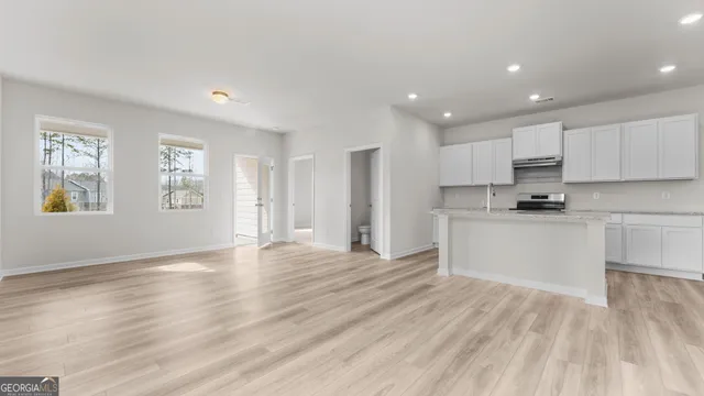 a view of an empty room with window and wooden floor