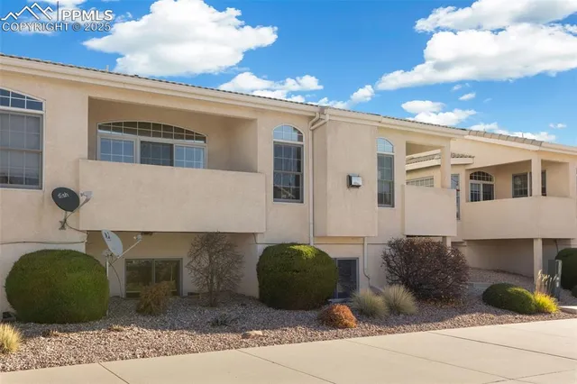 a view of a white house with large windows and a table and chairs