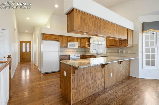 a kitchen with stainless steel appliances granite countertop a sink a microwave a refrigerator and cabinets