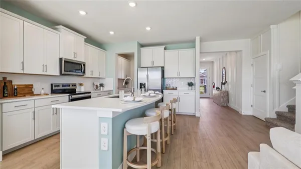 a kitchen with stainless steel appliances granite countertop a stove a sink a microwave a refrigerator and white cabinets