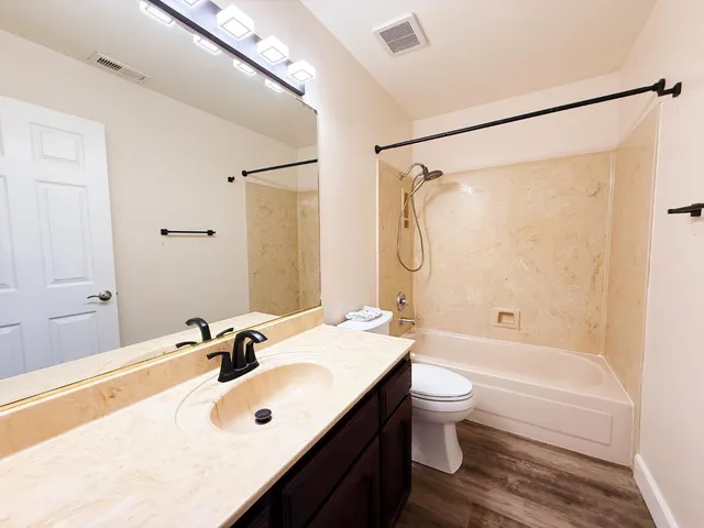 a bathroom with a bathtub shower sink mirror vanity and toilet