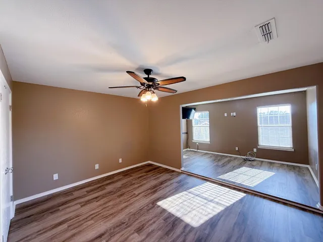 a view of an empty room with window and wooden floor