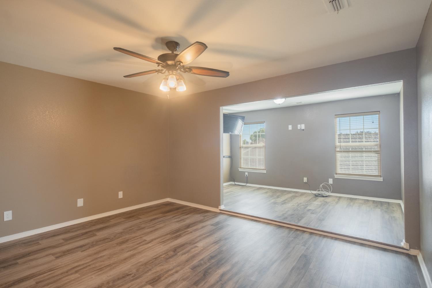 3147 Boulder Avenue Madera, CA 93637 - Photo 16 of 29 an empty room with wooden floor fan and windows