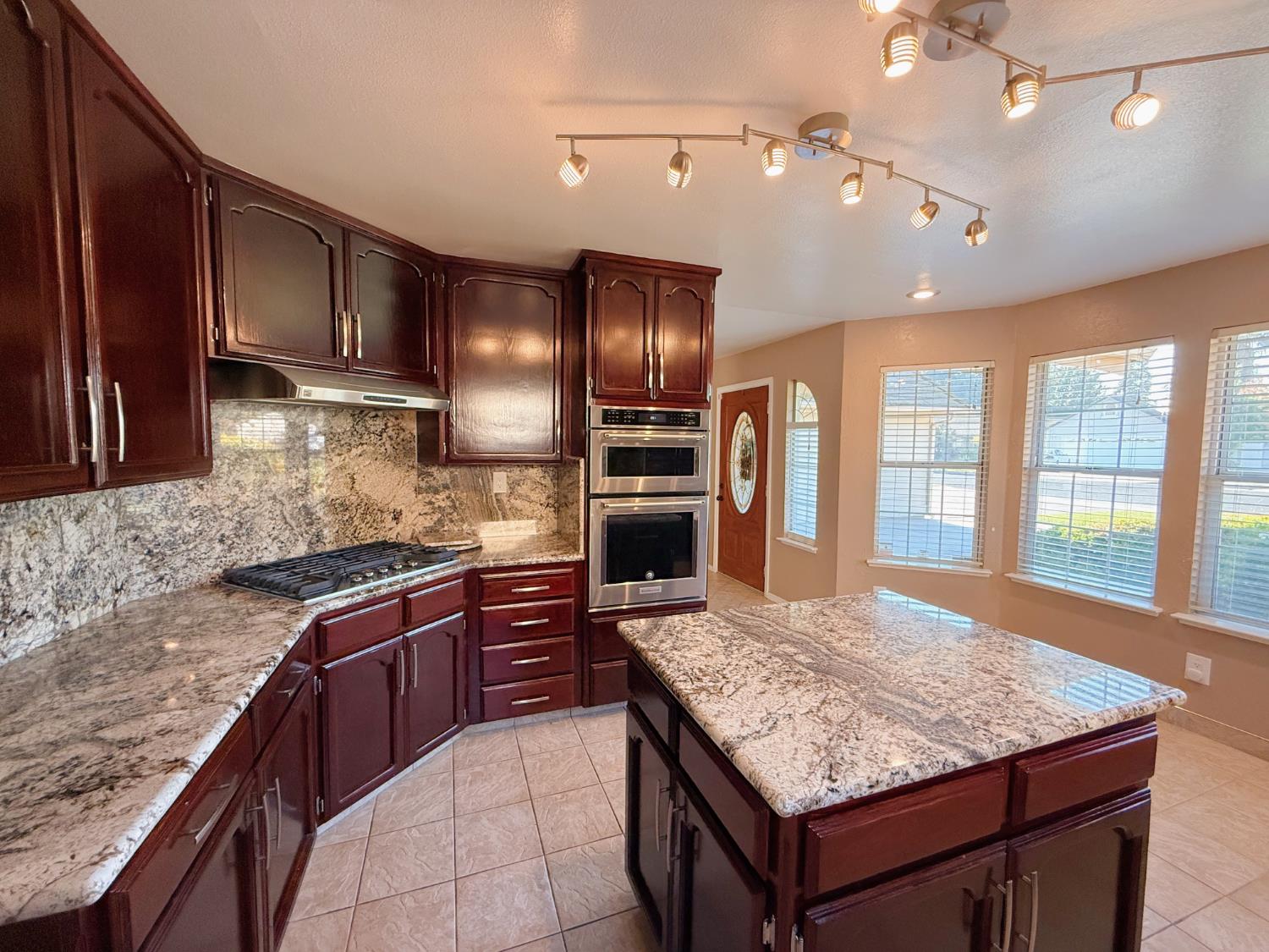 3147 Boulder Avenue Madera, CA 93637 - Photo 4 of 25 a kitchen with kitchen island granite countertop wooden cabinets and a refrigerator