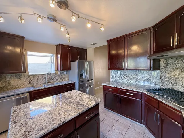 a kitchen with stainless steel appliances granite countertop wooden cabinets a oven a sink and dishwasher