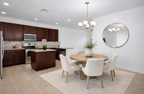 a dining room filled chandelier and kitchen view