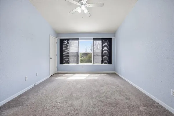 an empty room with windows and chandelier fan