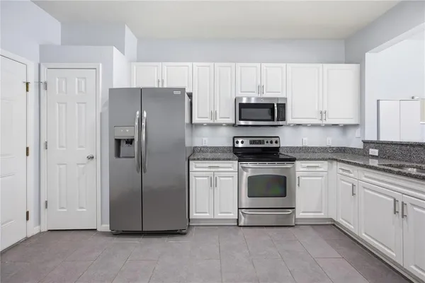 a kitchen with granite countertop white cabinets and stainless steel appliances