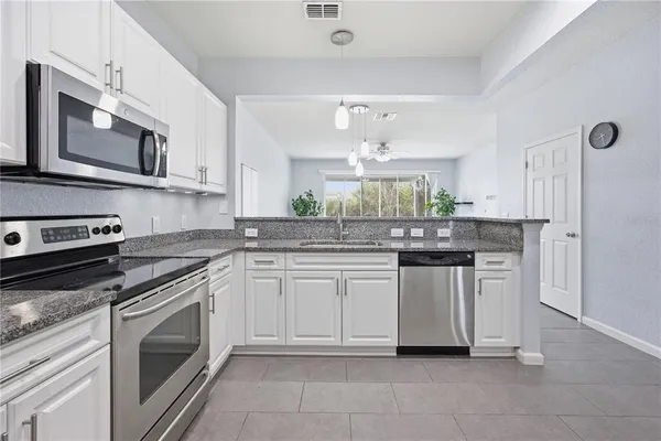 a kitchen with stainless steel appliances granite countertop a sink and dishwasher a stove top oven with white cabinets