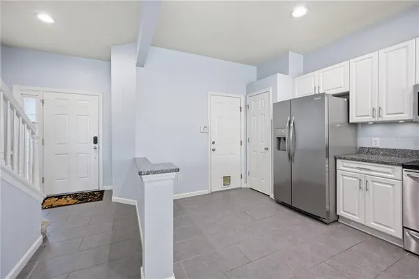 a view of a kitchen with refrigerator and white cabinets