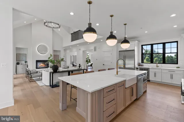 a large white kitchen with a large island oven a stove a sink a clock and a large window