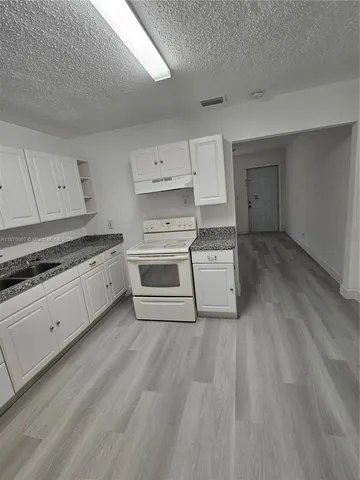 a kitchen with granite countertop white cabinets and white appliances
