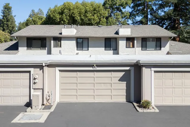 a view of a white house with large windows and a small yard
