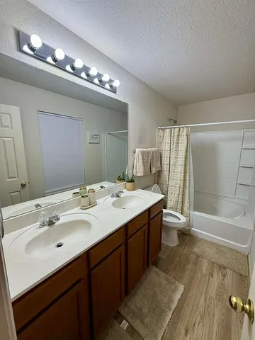 a bathroom with a double vanity sink a large mirror and a bathtub