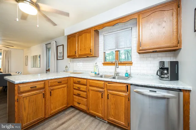 a kitchen with stainless steel appliances granite countertop wooden cabinets a sink a stove a dining table and chairs