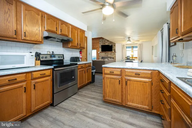 a kitchen with stainless steel appliances granite countertop a refrigerator a sink dishwasher and wooden cabinets with wooden floor