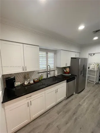 a kitchen with granite countertop a sink a refrigerator and cabinets