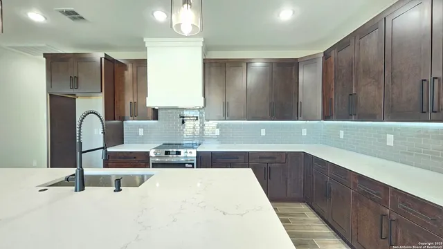 a kitchen with stainless steel appliances kitchen island granite countertop a refrigerator and a sink