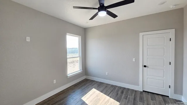 a view of empty room with wooden floor and fan