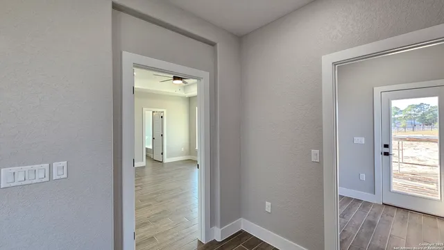 a view of a hallway with wooden floor and a room