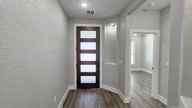 an empty room with wooden floor closet and windows
