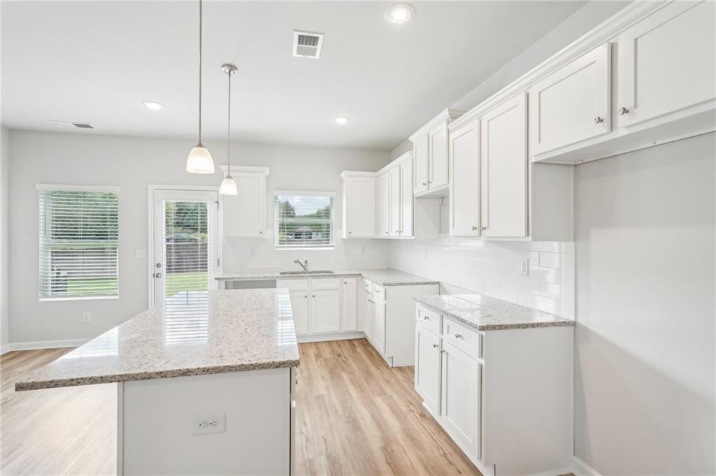 3002 Viewpark Circle Conyers, GA 30013 - Photo 14 of 41 a kitchen with stainless steel appliances granite countertop a sink a stove and white cabinets with wooden floor