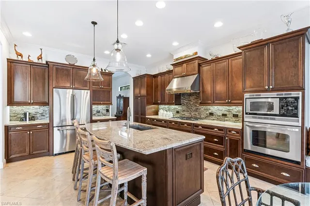 a kitchen with stainless steel appliances kitchen island granite countertop a stove a refrigerator a oven a sink with a dining table and chairs