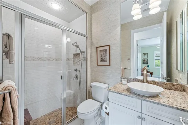 a bathroom with a granite countertop sink toilet a mirror and shower