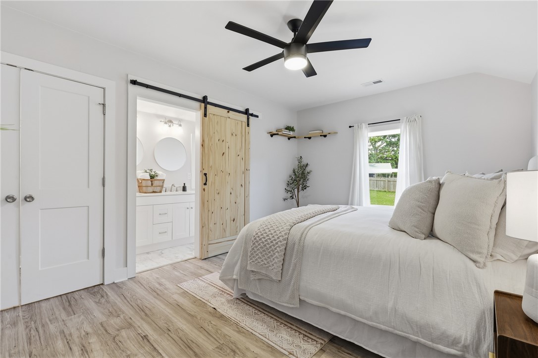 1 Brock Street Pelzer, SC 29669 - Photo 14 of 25 A private bedroom retreat offers easy access to a well-appointed bathroom through a rustic barn door.
