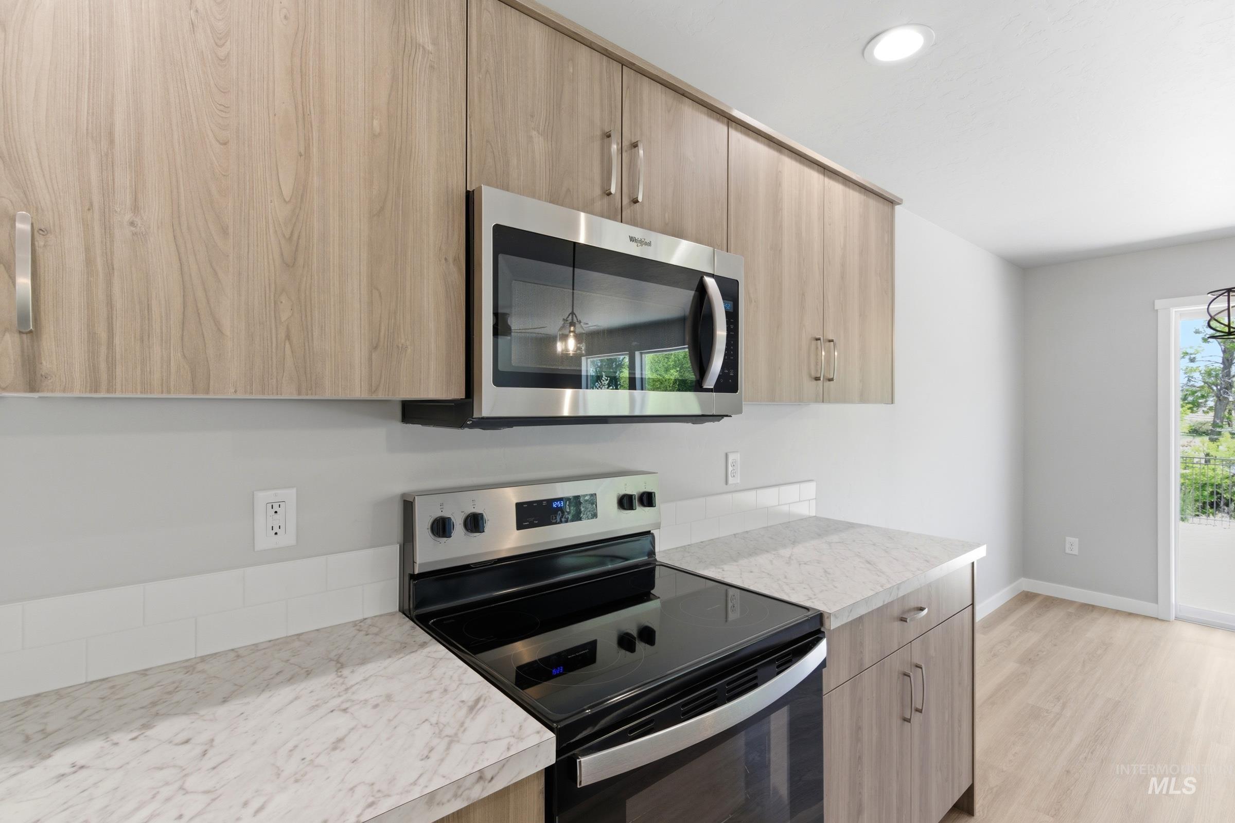 2374 West Fallon Loop Nampa, ID 83651 - Photo 5 of 24 Kitchen featuring wood-finish cabinetry, stainless steel microwave, black electric range, and light-toned countertops
