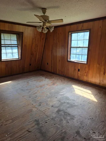 an empty room with windows chandelier fan and windows