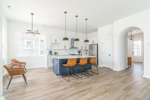 a kitchen with stainless steel appliances granite countertop a stove a sink a kitchen island with a dining table and chairs