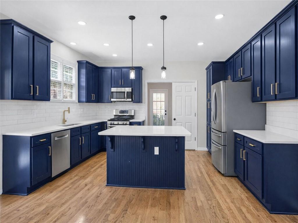 8840 Appling Ridge Cumming, GA 30041 - Photo 25 of 87 a large kitchen with wooden floors stainless steel appliances a sink a counter top space and cabinets