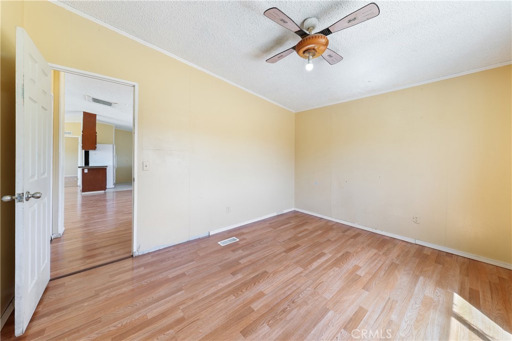 8195 Alta Mesa Road Oak Hills, CA 92344 - Photo 14 of 33 an empty room with wooden floor and a ceiling fan