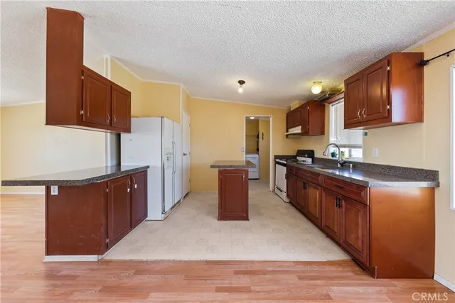 a kitchen with stainless steel appliances granite countertop a stove a sink dishwasher and a refrigerator with wooden floor