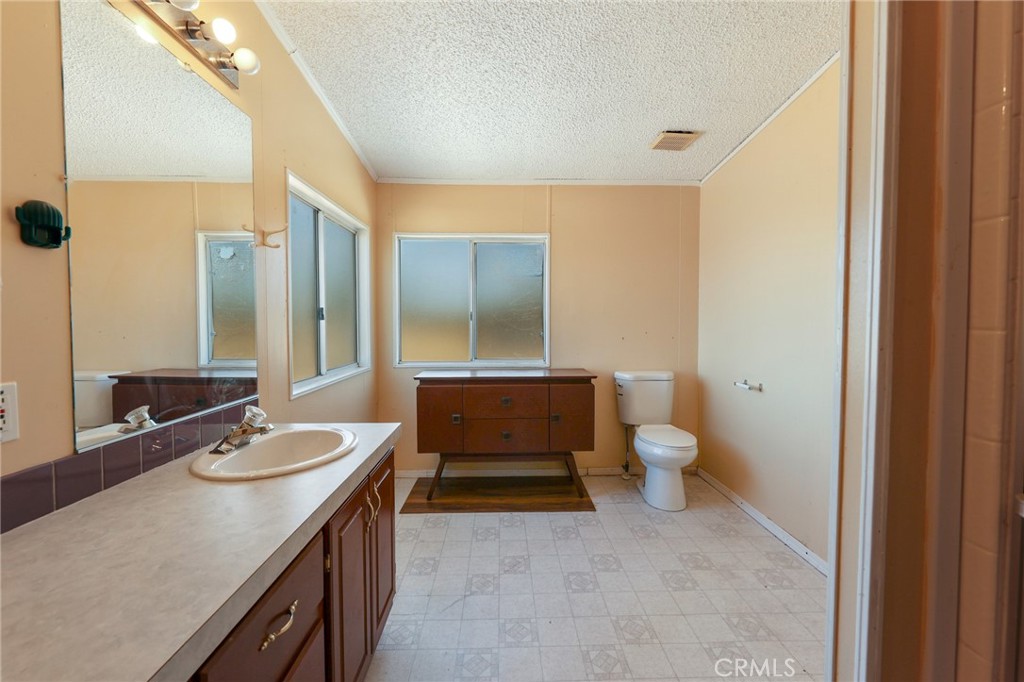8195 Alta Mesa Road Oak Hills, CA 92344 - Photo 5 of 33 a bathroom with a sink a toilet and mirror